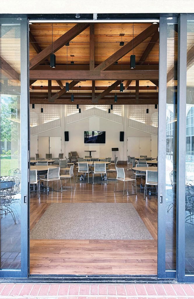 Spacious event hall with high wooden ceilings, modern chairs, and audiovisual equipment.