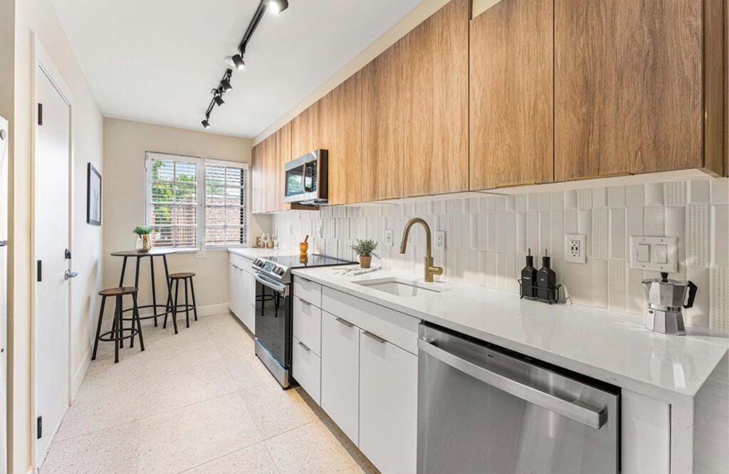 Bright, stylish kitchen with white counters, wooden upper cabinets, and stainless steel appliances.