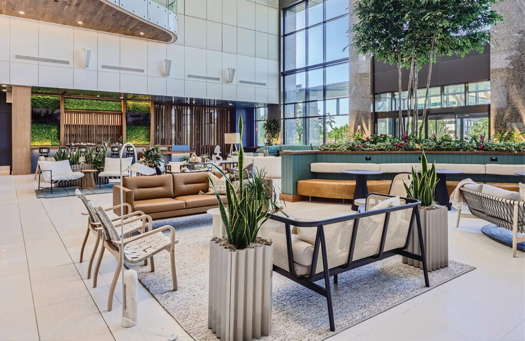 Bright, spacious hotel lobby interior with contemporary furnishings, indoor plants, and abundant natural light.