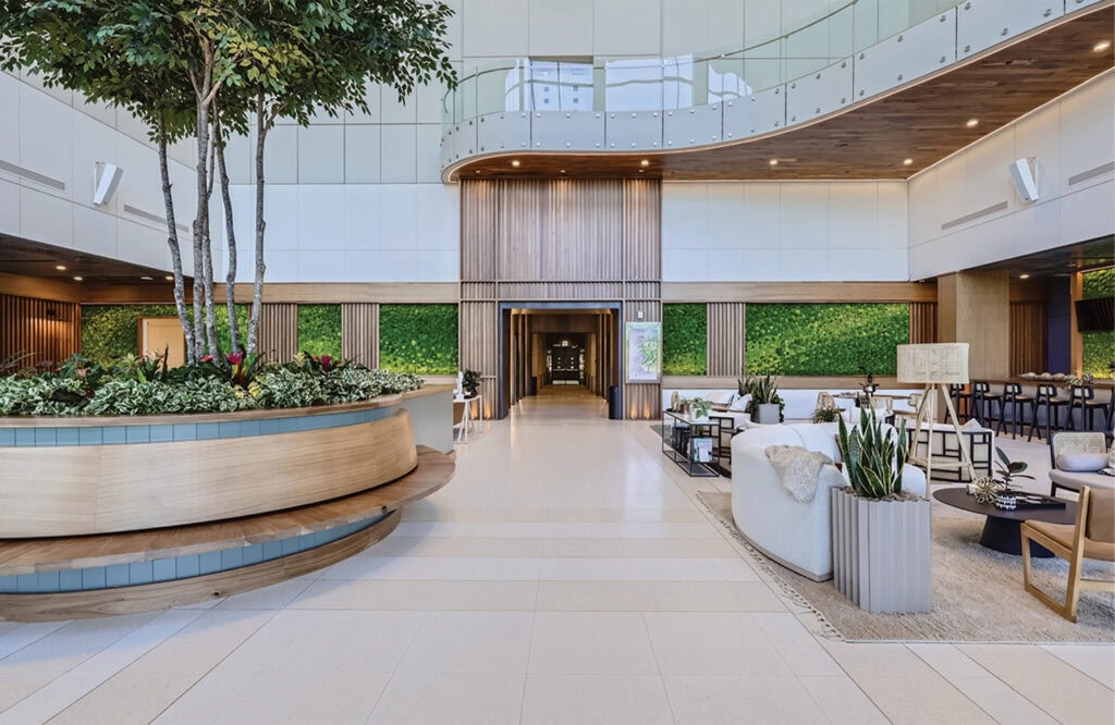 Elegant hotel lobby with lush green plants, cozy seating, contemporary decor, and natural lighting.